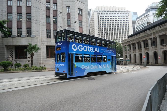 A blue double-decker Hong Kong tram wrapped in "Gate.AI - One Gate to All AI" advertising, traveling along tracks with colonial-style buildings and skyscrapers in the background.