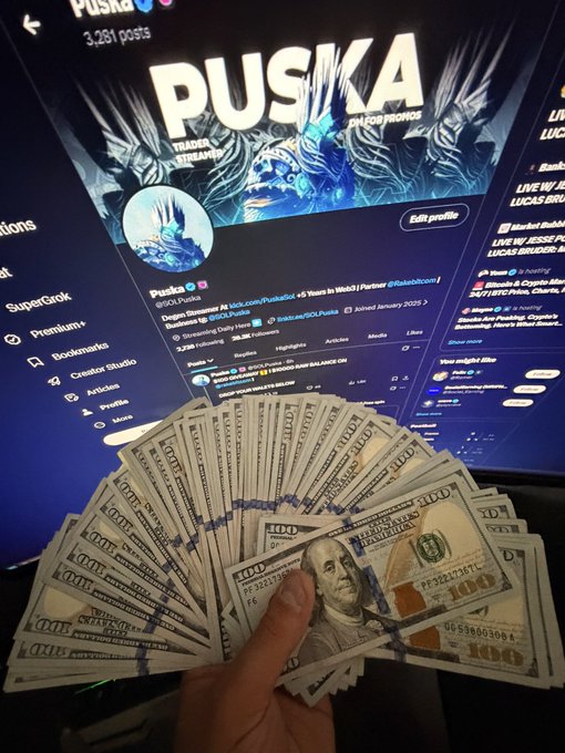 A hand fans out a large stack of $100 bills in front of a monitor displaying the X/Twitter profile of 'Puska' (@GOLDXRPuska), tagged as 'TRADER / STREAMER' and 'XRP CRYPTO', showing 3,261 posts.