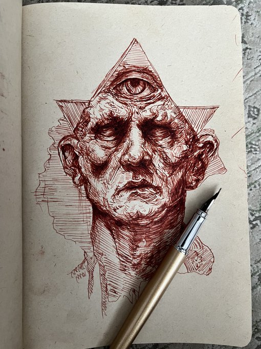 An intricate red ink sketch in a notebook depicts an aged, weathered face with a third eye on its forehead, surrounded by a triangular and star-shaped frame, with a fountain pen resting on the page.