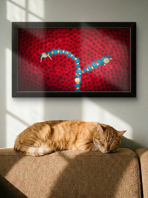 An orange tabby cat sleeps peacefully on the back of a brown couch beneath a framed picture of a blue snake-like creature on a red honeycomb background.