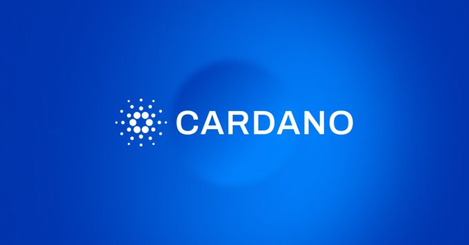 The image features a blue background with white text that reads "Cardano". The text is centered within the frame, making it the main focus of the image. Below the text, there's an announcement about Cardano trading hours, stating that they are available 24/7 and that institutional access to the cryptocurrency exchange is required for trading.