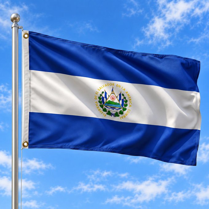 The flag of El Salvador flies against a blue sky, displaying its blue-white-blue horizontal stripes and central coat of arms with the inscription "REPÚBLICA DE EL SALVADOR EN LA AMÉRICA CENTRAL." The image accompanies news about El Salvador's adoption of a digital dollar app built on Coinbase's Base network, visually reinforcing the nation leading the integration of blockchain technology into its official financial infrastructure.