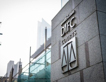 A building sign in Arabic and English reading 'DIFC COURTS' with a justice scales emblem, set against a backdrop of modern glass skyscrapers.