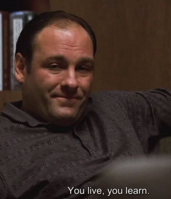 A man with dark hair wearing a gray patterned polo shirt is shown in what appears to be an office setting, with the subtitle "You live, you learn." displayed at the bottom of the frame.