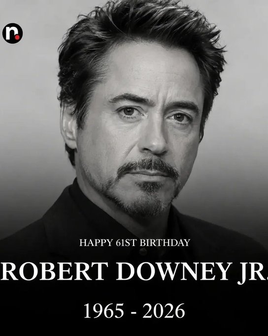 A black-and-white portrait of Robert Downey Jr. smiling warmly, with text reading "HAPPY 61st BIRTHDAY ROBERT DOWNEY JR. 1965 - 2026" celebrating the legendary American actor as described in the accompanying tribute.