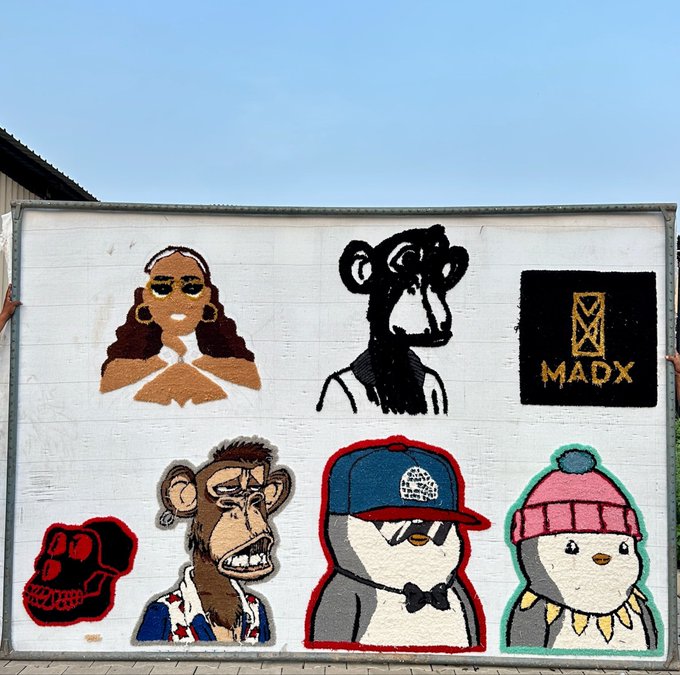 An outdoor mural painted on a white wall featuring several characters including monkeys, a penguin in a hat, and a red skull, alongside the text 'MADX'.