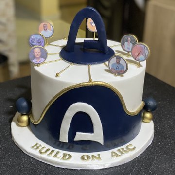 A decorative cake designed to resemble an arcade machine, featuring a blue and white color scheme with a "BUILD ON ARC" inscription on the base and small photo cutouts of people on top. The post suggests the cake was created by or for @0x_manny1, likely celebrating a milestone or event related to the Arc project or community.