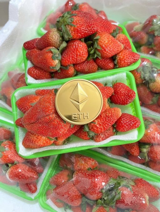 The image features an arrangement of strawberries that includes a large number "1" alongside the strawberries. The strawberries are displayed within two green plastic containers filled with white material, which could be a tray or a sheet. A gold coin lies on top of these strawberry containers as well. A post below the image states, "ETH = 200k, that' s from 10 years ago. Now things are different, so where will the price go in 10 years, 2036? Strawberries 300k/kg." which hints at the value and market price for strawberries over time.