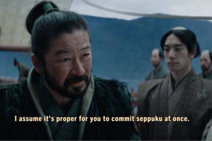 The image features a man with a long beard wearing a black outfit, standing next to another person who has short hair. They are both looking at something off-camera, possibly engaged in conversation or observing an event. The caption below the image reads "I assume it's proper for you to commit seppuku at once." This suggests that the man with the long beard might be discussing a cultural practice or custom related to seppuku (Japanese sword fighting) and how it is perceived by others, including the person in front of him.