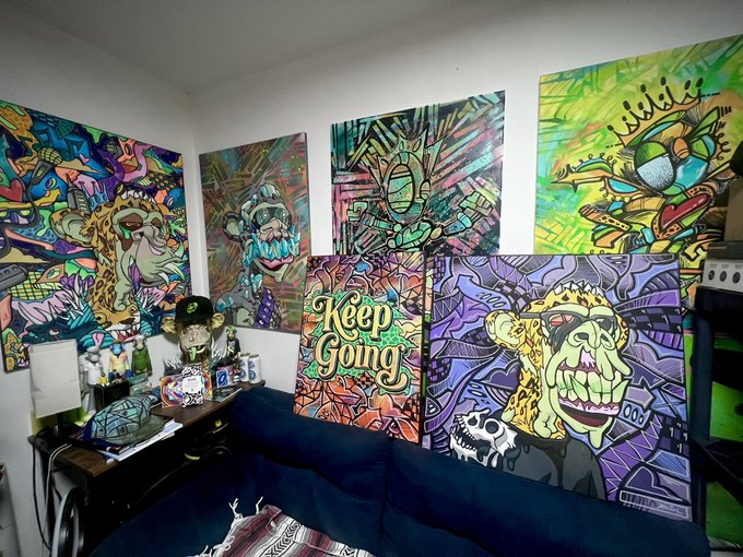 The image features a living room with a blue couch, where several paintings are displayed on the walls above it. There are four distinct paintings hanging at various heights, showcasing different styles and themes. The room also contains other items such as a lamp, a bottle, and a book, which contribute to the overall atmosphere of the space. 

The post "Remember to Always keep going!" is related to the image in that it encourages viewers to persevere through challenges or setbacks, just like the monkey who keeps going despite obstacles. The monkey's determination can be seen as an inspiration for those facing difficulties in their lives.