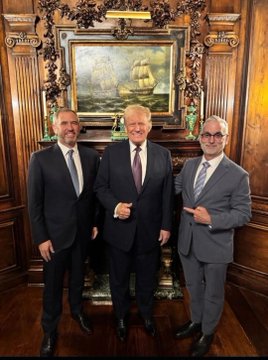 Three men in formal suits pose together in an ornately decorated room with wood paneling and a framed ship painting behind them; the post suggests the image is connected to a hidden "plan" for XRP being larger than commonly perceived.