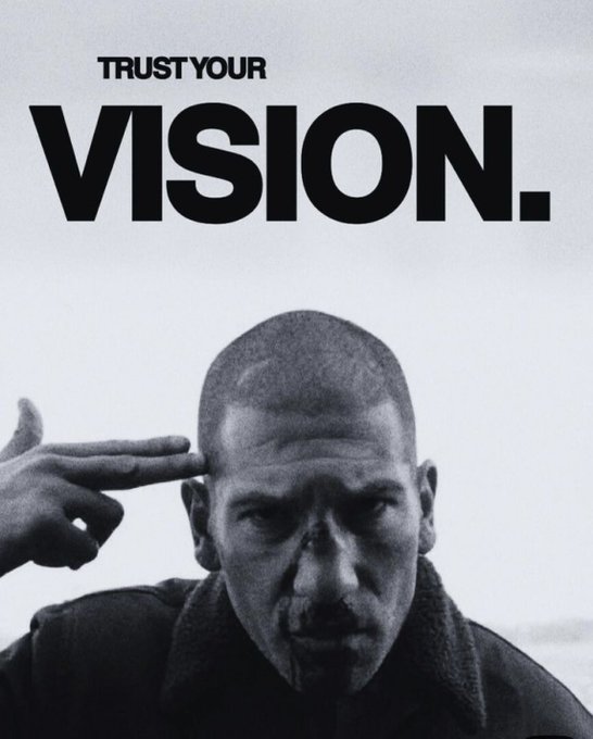 A black and white motivational image featuring a man pointing to his temple with the bold text 'TRUST YOUR VISION.'