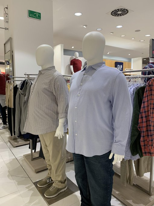 Two male mannequins display casual button-down shirts and jeans in what appears to be a GAP retail store.