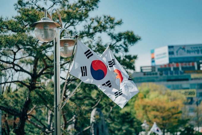 The image shows flags of South Korea, suggesting a connection to the post about Japan and XRP adoption. The post claims Japan's huge economy leads in XRP adoption after reclassifying it as a regulated financial product.