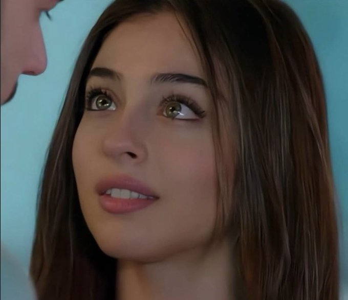 A close-up shot of a young woman with long brown hair looking up at someone off-camera with an attentive expression.