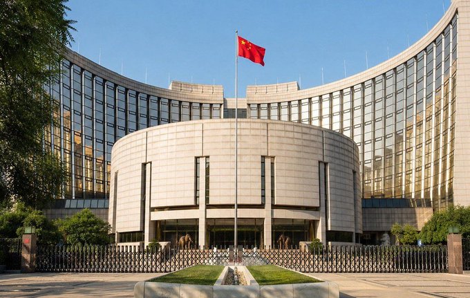 A large curved government-style building with a Chinese flag flying on a flagpole in front, featuring a semi-circular facade and metal gates at the entrance.
