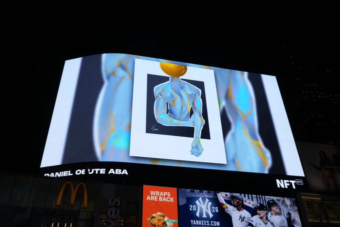 A brightly lit digital billboard in New York showcases a blue and yellow figure artwork at NFT NYC, with partial text reading "DANIEL OF UTE ABA" visible, while below, a McDonald's logo and a Yankees advertisement reading "WRAPS ARE BACK" and "YANKEES.COM" are displayed against the night sky.