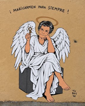 A street art mural depicting a figure with white angel wings and a golden halo sitting on a gray cube, holding a cross, with the text '¡MARICARMEN PARA SIEMPRE!' painted above.