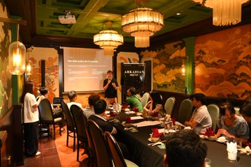 A meeting takes place in a dimly lit room with Chinese-style decor, where a presentation screen displays "The First Order of all Powers" and "A.R.K.ASIA".