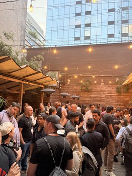 A crowd of people gather at an outdoor venue with string lights and umbrellas, likely at the AVAX Summit after party, as suggested by the post celebrating the event's completion.