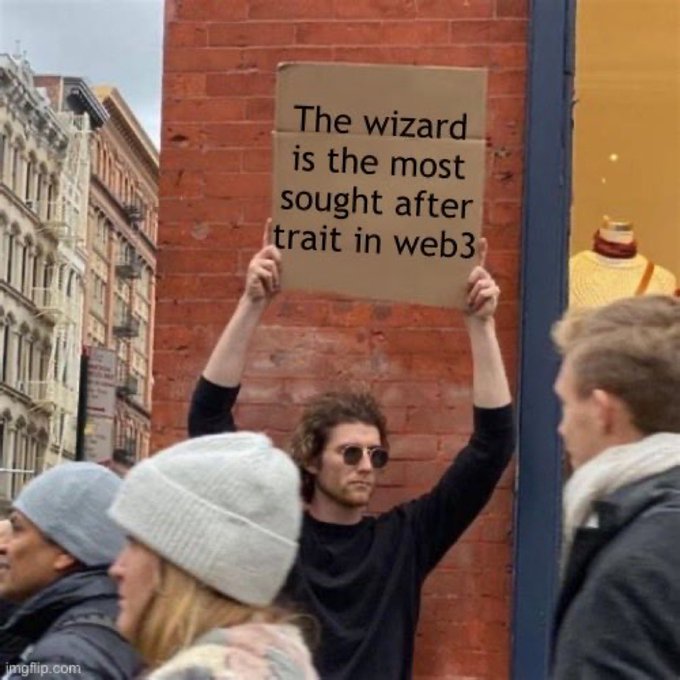 A meme showing a man holding a cardboard sign that reads 'The wizard is the most sought after trait in web3' on a city street.