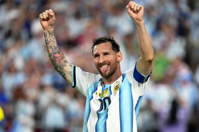 The image shows a man wearing a blue and white striped shirt with his arms raised, celebrating. The background reveals that he is at a soccer match or event where fans are present. The caption suggests that the focus should be on the relationship between FIFA and @FIFAcom rather than the content of the post itself.