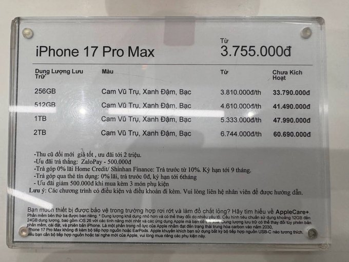 A printed price list for the iPhone 17 Pro Max displayed in Vietnamese, detailing prices ranging from 3.755.000đ to 6.744.000đ depending on storage capacity (256GB to 2TB) and color options.