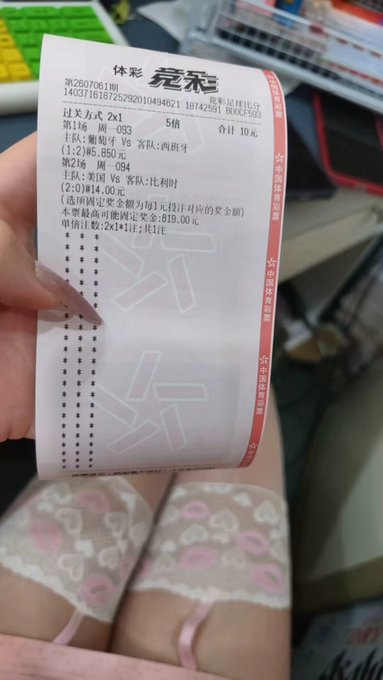 A hand holding a Chinese lottery receipt from 体彩 (Sports Lottery) showing numbers 1-26-093, with the person wearing pink Hello Kitty-patterned socks visible below.