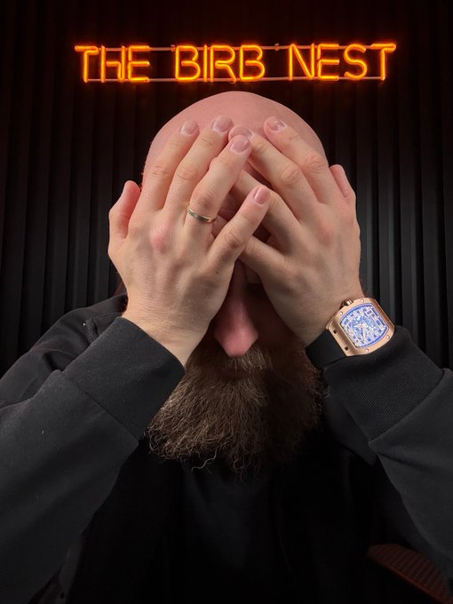 A bearded man with a ring and luxury watch covers his face with both hands beneath a glowing orange neon sign reading "THE BIRD NEST," visualizing the overwhelming regret of a trader who missed gains on one asset that outperformed their chosen pick.