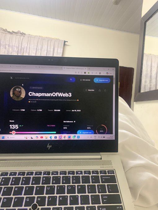 An HP laptop sitting on a bed displaying the X (formerly Twitter) profile of 'ChapmanOfWeb3' (@ohicdm), showing a score of 135 with followers, tweets, and account join date of Jan 15, 2022.