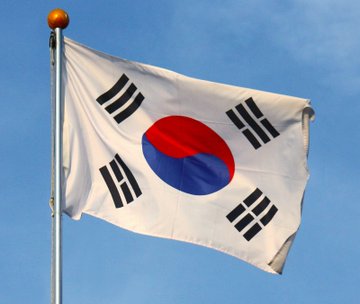 The flag of South Korea is displayed, representing KB Financial's Kookmin Bank's adoption of JPMorgan's Kinexys for near-24/7 USD cross-border payments, marking a significant move into blockchain technology.