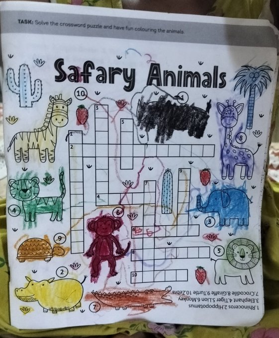 A child's completed 'Safari Animals' crossword puzzle worksheet featuring crayon-colored animals including a hippo, giraffe, lion, elephant, monkey, turtle, rhino, and crocodile.