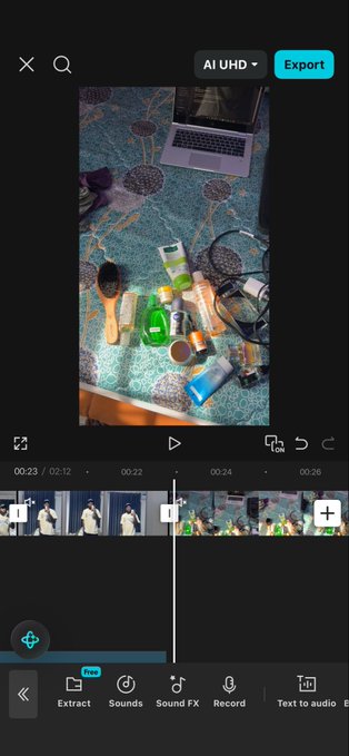 A video editing app interface displays a clip of toiletries and a laptop on a patterned carpet, with editing tools visible at the bottom.