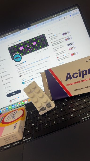 On a MacBook displaying X (formerly Twitter), various medications including Acipip 5, Augmentin 625, and Atorva 40 are arranged on the keyboard, alongside the social media feed showing posts about building AI tools and digital business strategies. The image juxtaposes pharmaceuticals used for treating illness with active social media engagement, reflecting the caption's theme of being unwell yet still seeking opportunities or signals online.