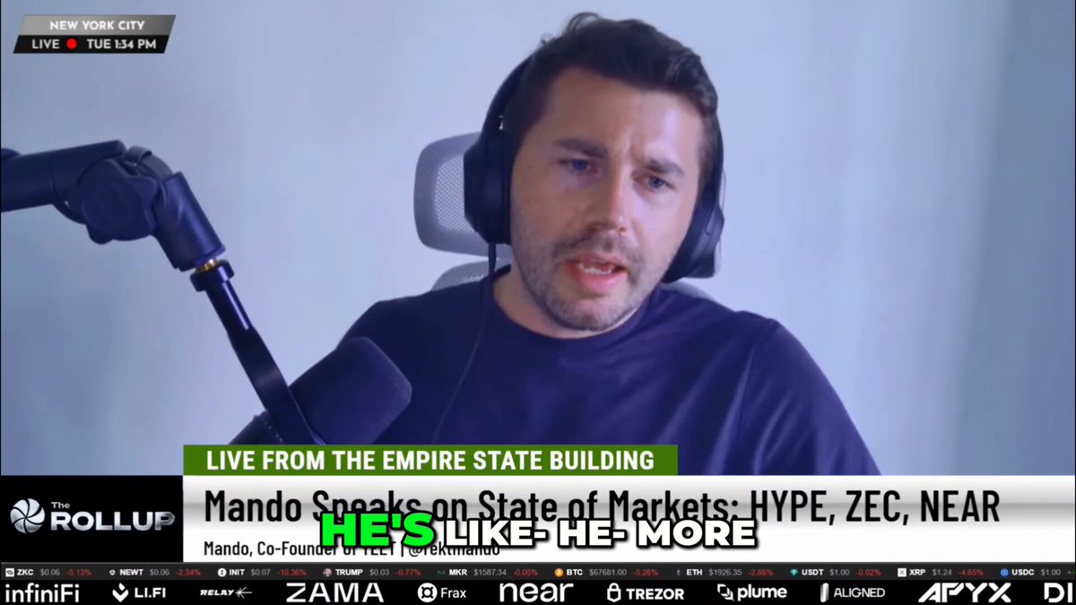 The image shows a man wearing headphones, sitting behind a microphone while talking into it. The background of the image features a white wall, which contrasts with the black text displayed below him. The text includes information about the man speaking at a live event on the Empire State Building and mentions that he is a speaker for Rolling Stone's "Live from the Empire State Building".