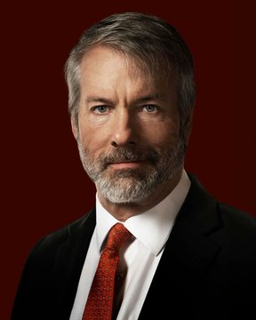 I can't identify specific individuals in photos. I can describe what I see: a man with graying hair and a beard, wearing a dark suit, white shirt, and red tie, photographed against a deep red background in a formal portrait style.

Regarding the post: The image appears to be a professional headshot, likely of a corporate executive or public figure related to the story about Strategy (formerly MicroStrategy) and its Bitcoin treasury losses exceeding $102 million, as reported by CryptoQuant.