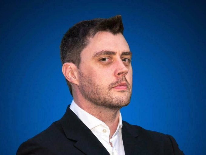 A portrait of a man in a dark suit and white shirt against a blue backdrop, identified as Andre Cronje, founder of Sonic and Flying Tulip, pictured here in connection with his remarks on using Flying Tulip to address onchain liquidity challenges for real world asset adoption.
