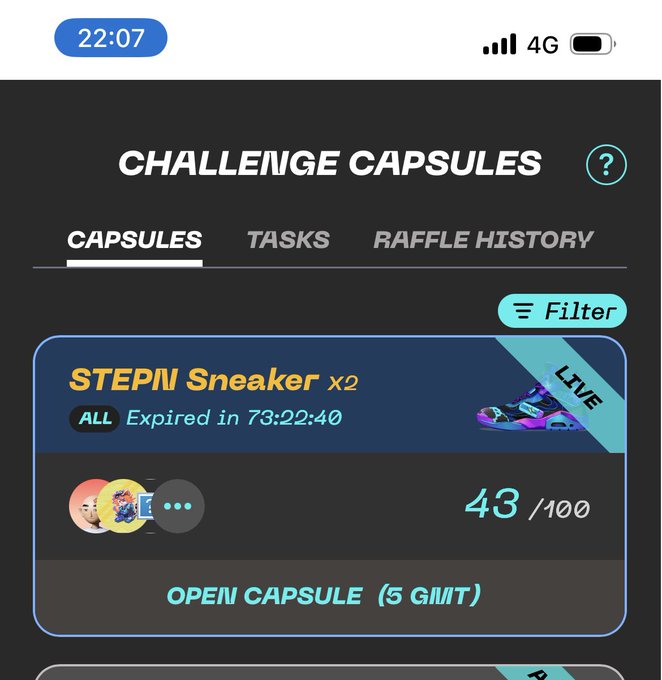 The image shows a phone screen displaying information about a challenge capsules product, specifically a sneaker. The sneaker has a purple and blue color scheme with a unique design. The phone's screen also displays the time of the day as 22:07 and the battery level at 4G. There is an open caption box on the screen that reads "OPEN CAPSULES (5 gilt)".