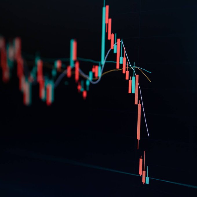 A dramatic stock chart shows a candlestick pattern with a sharp plunge of red bearish candles crashing downward from a peak, visually representing the 29% nosedive of a Nasdaq-listed stock following its announcement of a Bitcoin acquisition plan. The steep decline, emphasized by moving average trendlines curving downward, captures the market's negative reaction to the crypto-buying strategy.