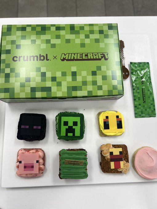 A box of 'crumbl x MINECRAFT' cookies featuring pixelated designs of a creeper, enderman, bee, pig, slime, and axolotl.