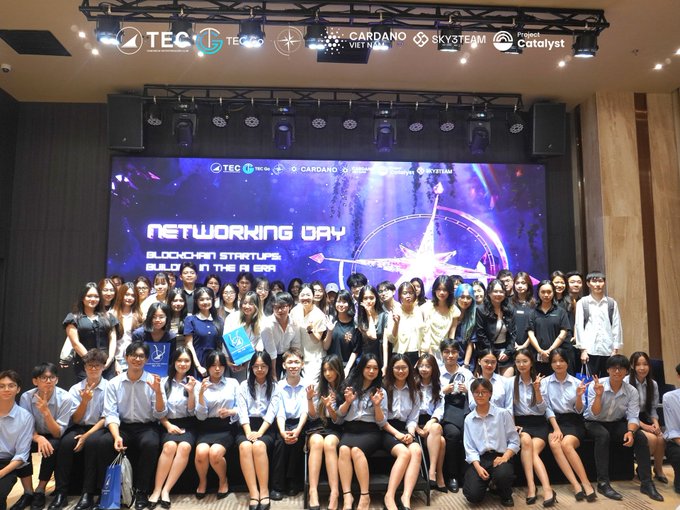 A large group of attendees pose on stage at the Cardano Networking Day 2026, with the event's "Networking Day: Blockchain Startups Building in the AI Era" backdrop visible behind them alongside sponsor logos including Cardano, SkyTeam, and Project Catalyst. The image captures the community of ecosystem builders and founders gathered to explore Web3 and AI integration, reflecting the collaborative spirit highlighted in the post.