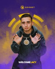 The image features a man wearing a hoodie, standing against a purple background that includes yellow circles. The man has his hands up in front of him, with one hand holding a gold chain around his neck. The text "Lacy" is written on the poster, and it appears to be promoting an upcoming collaboration between Roobet and a person named Lacy.
