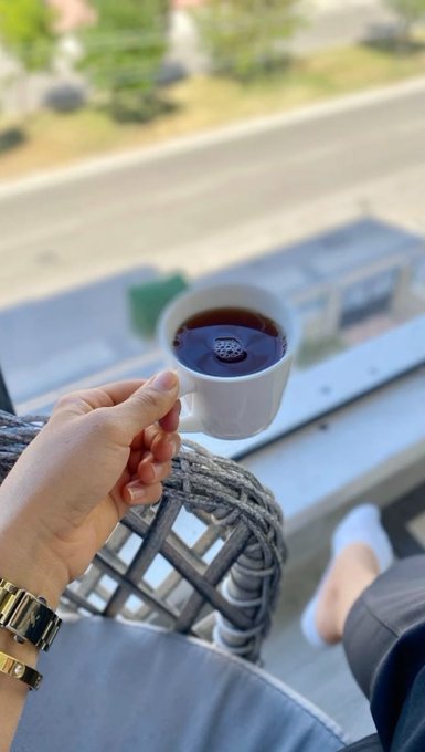 A person holding a cup of coffee while sitting outside, possibly enjoying their morning or afternoon break.