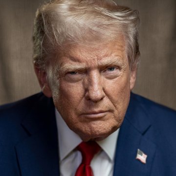 A close-up portrait of Donald Trump in a dark navy suit with a red tie and American flag lapel pin, set against a dark textured background.