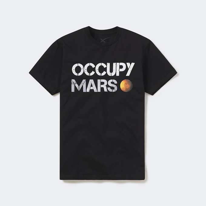 In the image, there's a black t-shirt that features an interesting design of the words " Occupy Mars" written across it with a picture of a planet below it. The text and the planets are all in white, giving the shirt a modern, bold look. This t-shirt appears to be related to the SpaceX event described in the provided caption, as it has been tagged by the company on their social media platforms during the event. The design represents support for space exploration and serves as a reminder of the progress made in this field over time.