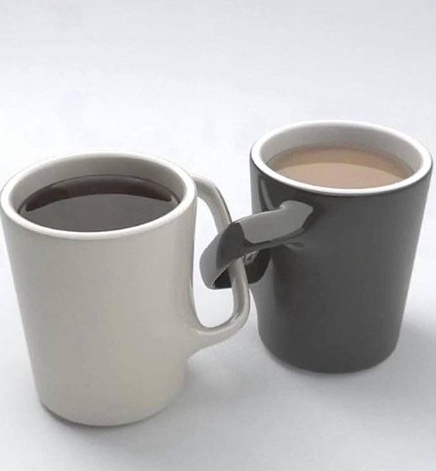 Two coffee mugs, one white and one black, sit side by side with their handles intertwined or connected in some way, both filled with what appears to be coffee.
