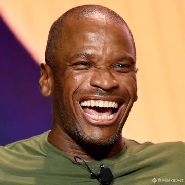A laughing Black man in a green shirt with a lapel microphone, captured by MarketVeat.