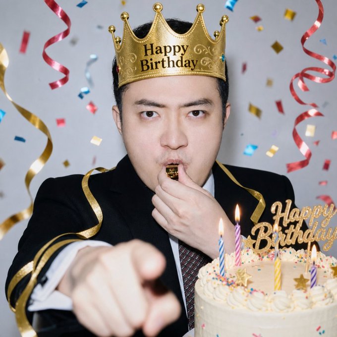A man wearing a gold 'Happy Birthday' crown blows a party horn while pointing at the camera, with a birthday cake featuring lit candles in front of him.