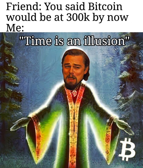 A meme featuring Leonardo DiCaprio's face edited onto a spiritual figure with outstretched arms, captioned "Friend: You said Bitcoin would be at 300k by now / Me: 'Time is an illusion'" with a Bitcoin symbol in the corner.