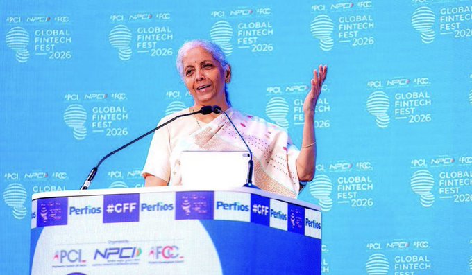 An older woman with short white hair speaks at a podium during the Global Fintech Fest 2026, with banners displaying logos for APCL, NPCL, and IFC visible in the background.